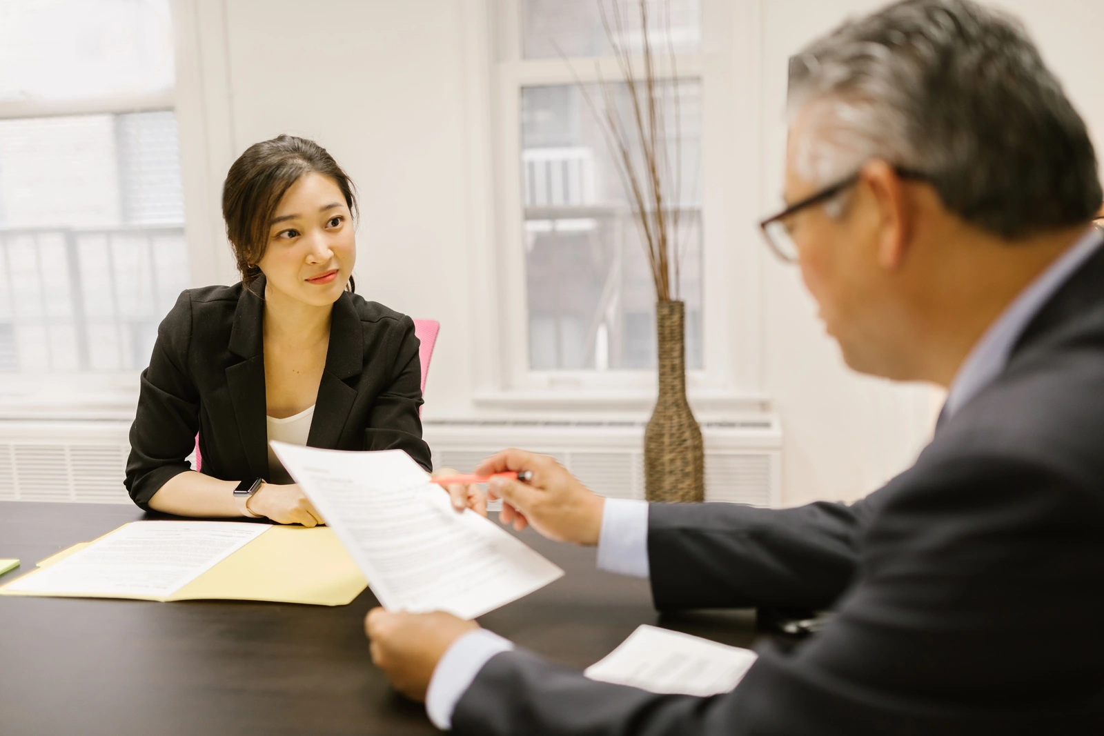 明るいオフィスで資料を確認しながら話を聞く女性と、説明する男性。ご相談のイメージ写真